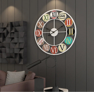 The Nordic Color-Ring Wall Clock, featuring mixed styles and vibrant colors for each number, hangs on a dark paneled wall above a sofa and beside a black floor lamp.