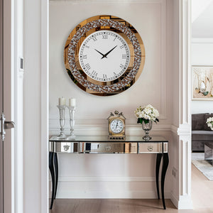 A Modern Luxury Roman Numerals Wall Clock hangs above a mirrored console table with candles, a smaller clock, and fresh flowers in a bright, modern hallway.