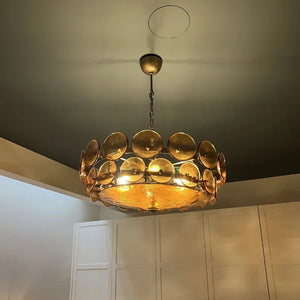 An Italian Retro Pendant Light with circular glass discs hangs from a dark ceiling above white cabinets in this modern room.