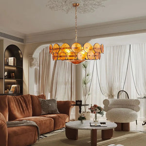 A modern living room with a brown velvet sofa, round marble coffee tables, a white textured chair, and an Italian Retro Pendant Light hanging from the ceiling.
