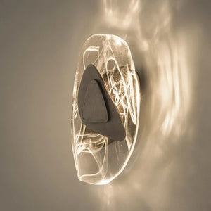 The Luxury Crystal Wall Lamp features a sculptural design with a glowing oval-shaped glass base, intricate wire-like details, and a central dark triangular accent, adding an artistic touch of sophistication to any space.