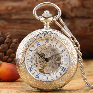 The Silvery Pocket Watch, featuring Roman numerals and a skeleton dial, rests on a surface with a pine cone and apple in the background.