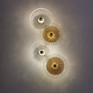 Four Amber Deco Wall Sconce fixtures with a circular design in gold and silver are mounted on the ceiling, casting soft, radiating shadows reminiscent of glass discs.