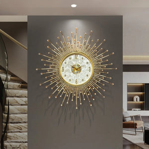 The Premium Sun Wall Clock, featuring a large gold sunburst design, is mounted on a gray wall in a modern interior with marble stairs and contemporary decor.