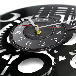 Close-up of a Black Record Wall Clock featuring white numbers and silver and red hands, with intricate gear designs in the background.