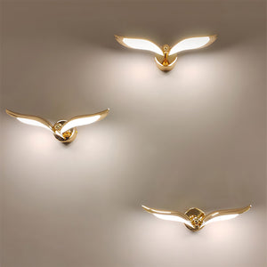 Three modern design gold wing shaped wall lights on an interior wall to mimic three birds flying in the sky.