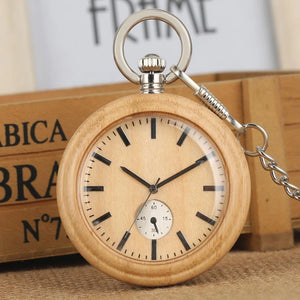 The Personalized Natural Minimalist Silver Bamboo Wood Pocket Watch Taschenuhr, featuring black hour markers, hands, a small seconds subdial, and a metal chain, rests elegantly against wooden boxes.