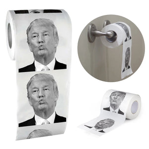 Trump Toilet Paper features repeated black-and-white images of Trump's face, displayed both on a holder and unrolled flat.