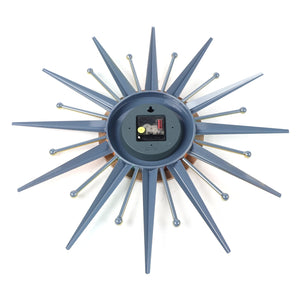 Back view of the Sunburst Wall Clock featuring its battery compartment, central mechanism, and blue-gray rays with gold accents radiating outward.