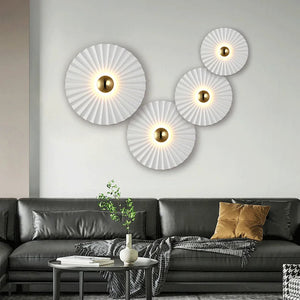 Modern living room with a black sofa, decorative pillows, a small plant on the coffee table, and four Origami Circle Wall Lights with gold accents, adding an elegant touch to the space.