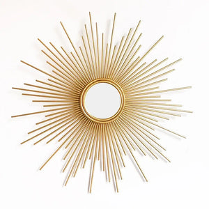 The Luxe Sunray Wall Mirror features a round design with a gold sunburst frame and metal rods of varying lengths, making it a perfect statement piece for modern interiors.