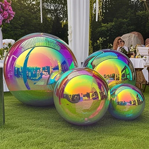 Four large Inflatable Gazing Balls display stunning iridescence on the grass at an outdoor event, serving as eye-catching garden decor among tables, decorations, and guests reflected in their surfaces.