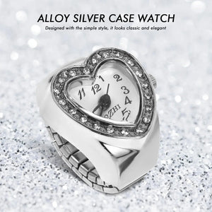 The Sweetheart Ring Watch, a heart-shaped accessory with rhinestones on the face displaying 11:12, rests on a glittery surface. Its romantic alloy silver case makes it perfect for rhinestone jewelry lovers.