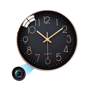 The Wall Clock SpyCam is a round black quartz wall clock that shows the time 10:08 and discreetly houses a hidden camera with HD 1080P resolution. An illustration indicates the camera lens and light beam located on the clock's lower left side, making it ideal for covert motion detection.