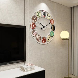 The Nordic Color-Ring Wall Clock, featuring vibrant hues and a mix of Roman and English numerals, hangs on a beige wall beside a floor lamp and a TV.