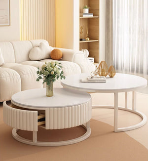 The Luxury Round Coffee Table Set, featuring sleek white round tables—one with a ribbed drawer and floral vase—is arranged in a bright living room with a beige sofa and stylish décor.