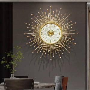 The Premium Sun Wall Clock with a decorative face hangs on a gray wall above a dining table, surrounded by chairs and a small green plant.