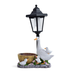 Introduce whimsical charm and gentle light to your outdoor space with the Solar Goose Lamp. This enchanting garden lamp post ornament showcases a graceful white goose accompanied by three ducklings, a petite planter bowl, and floral accents atop a stone-like base—making it an ideal addition to any cottage garden decor. The Solar Goose Lamp not only enhances your garden’s beauty but also provides soft solar-powered illumination for magical evenings outdoors.