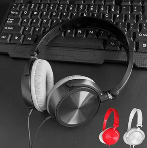 A pair of black Wired Bass Stereo Headphones with white ear pads rests on a keyboard, while red and white over-ear headphones can be seen in the bottom right corner.