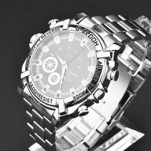 The Watch SpyCam is a silver stainless steel wristwatch with a round dial, multiple buttons, and a labeled bezel, featuring a hidden 1080P camera for discreet video and audio recording. It is displayed on a clear stand against a dark background.