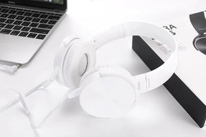Wired Bass Headphone with an ergonomic design rests on a white surface near a laptop and its box, delivering studio-quality sound.