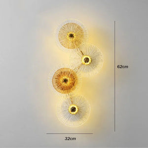 Amber Deco Wall Sconce features four circular, radiating glass discs in a wall-mounted LED design, illuminated from behind. The fixture measures 62 cm in height and 32 cm in width.
