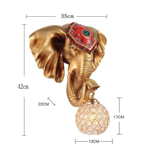 Enhance your space with the 3D Elephant Wall Light, showcasing a detailed red adornment and a spherical glass bulb held in its trunk. Dimensions: 35 cm width, 42 cm height; bulb is 13 cm wide and 17 cm high.