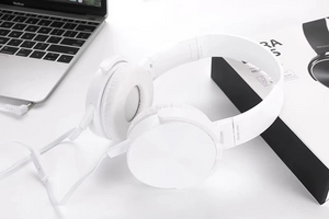 Wired Bass Headphone rests on a white surface near a laptop and its box, featuring studio-quality sound, ergonomic design, and a partially coiled visible cable.