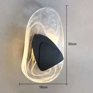 The Luxury Crystal Wall Lamp features a clear, irregularly shaped outer shell and a distinctive black triangular accent. Measuring 30 cm in height by 16 cm in width, it is showcased against a gray background. This stylish wall lamp brings an elegant touch to any interior.