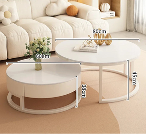 The Luxury Round Coffee Table Set, featuring two minimalist tables (60cm x 38cm and 80cm x 45cm), is arranged in the living room; one table displays a vase of flowers.