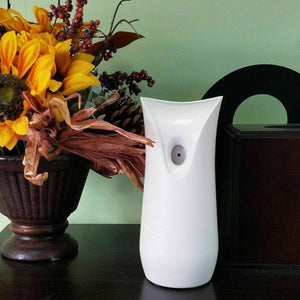 A White Decorative Display SpyCam seamlessly blends into a table setup with an air freshener dispenser, sunflowers, and dried flowers against a light green wall, exuding James Bond-level elegance and intrigue.