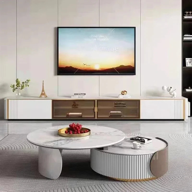 Modern living room with a wall-mounted TV, low white console, and two Luxe Round Coffee Tables—one holding a tray of berries and the other stacked with books.