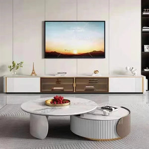 Modern living room with a wall-mounted TV, low white console, and two Luxe Round Coffee Tables—one holding a tray of berries and the other stacked with books.