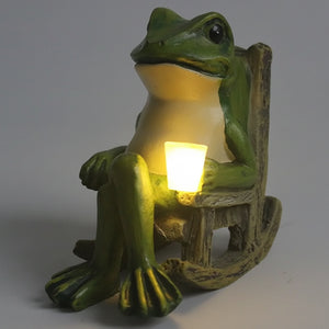 The Solar-powered Rocking Chair Frog Light features a weatherproof resin frog figurine sitting on a rocking chair, legs crossed and holding a glowing cup, making it the perfect garden frog ornament.