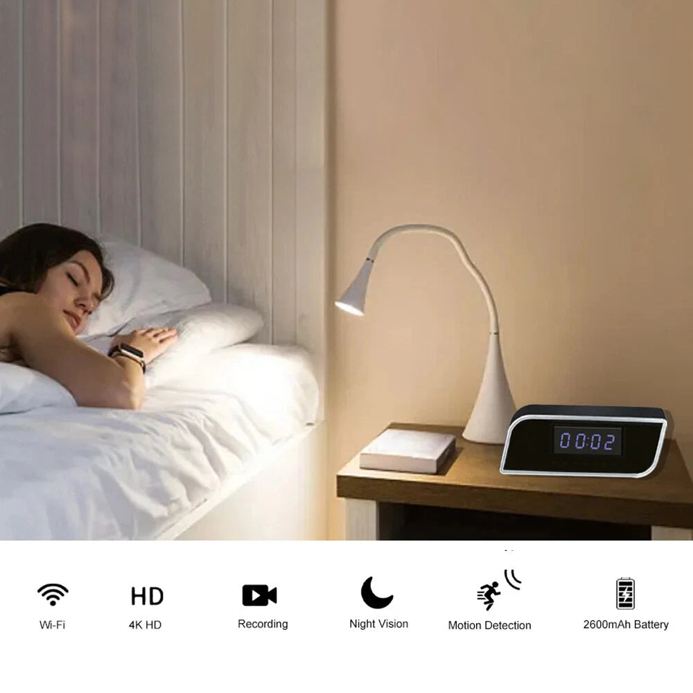 A woman sleeps in bed next to a nightstand with a lamp and the SpyCam Camera Clock; icons show features such as Wi-Fi, HD video, recording, night vision, motion detection, and long battery life.