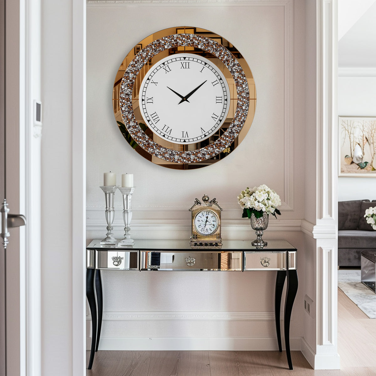 A Modern Luxury Roman Numerals Wall Clock hangs above a mirrored console table with candles, a smaller clock, and fresh flowers in a bright, modern hallway.