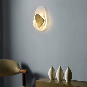 A Luxury Crystal Wall Lamp illuminates the space above a taupe cabinet adorned with three ceramic vases, while a beige chair sits nearby, all set against a gray wall.