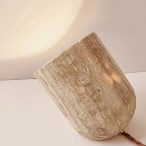 The Natural Stone Lamp, sculpted from yellow cave stone, lies on its side and casts a gentle, warm glow against a neutral background.