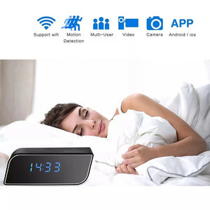 A woman sleeps in bed beside a SpyCam Camera Clock showing 14:33; above, icons highlight features such as WiFi, motion detection, video, camera, and mobile app support.