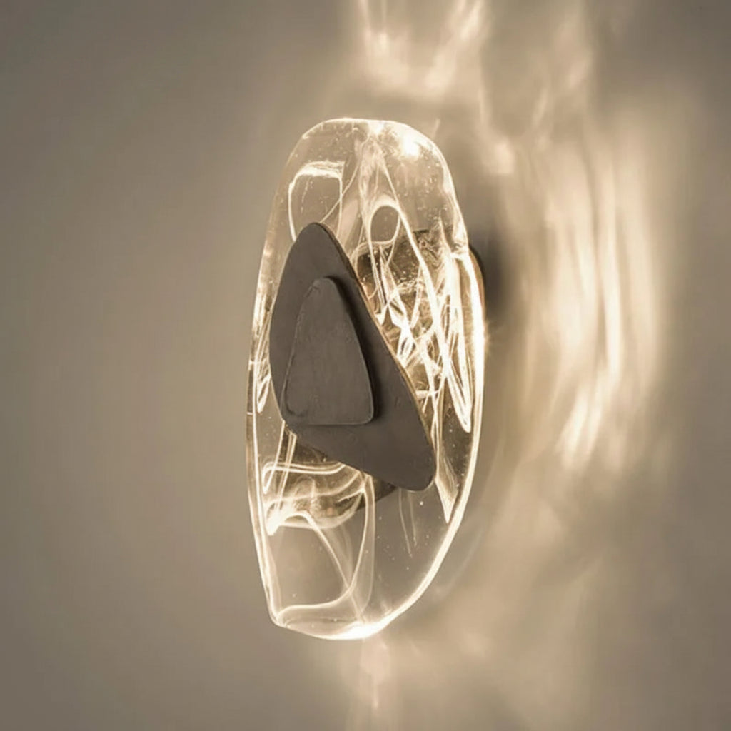 The Luxury Crystal Wall Lamp features a sculptural design with a glowing oval-shaped glass base, intricate wire-like details, and a central dark triangular accent, adding an artistic touch of sophistication to any space.