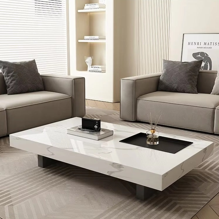 A modern living room with two grey sofas, neutral decor, and the Modern Luxe Coffee Table in white marble, styled with books, a framed print, and cushions.