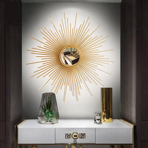 The Luxe Sunray Wall Mirror hangs above a white console table with two drawers, adorned with a glass terrarium, gold vase, and small sculpture—bringing statement interior design to life.