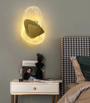 A Luxury Crystal Wall Lamp is mounted above a bedside table decorated with books, a small sculpture, and an hourglass, while a houndstooth-patterned headboard provides a stylish accent to the scene.