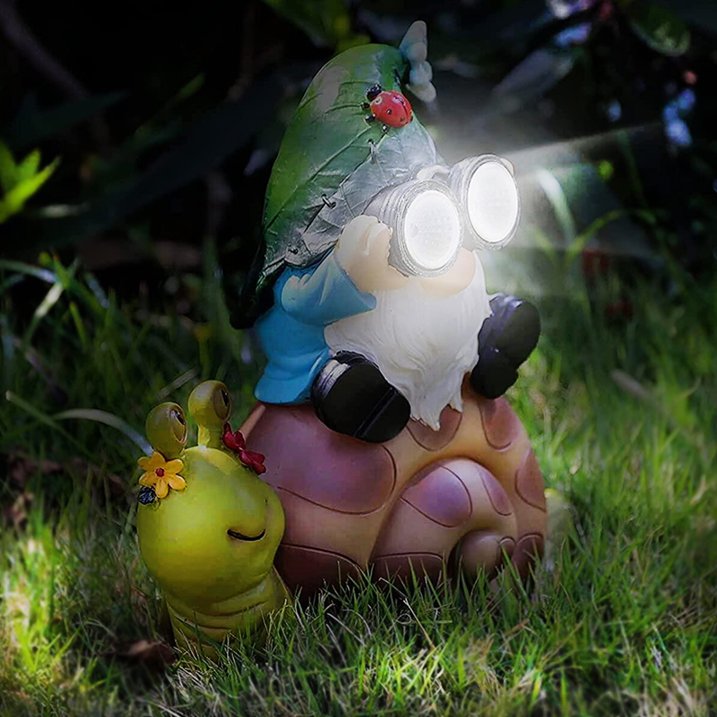 Add whimsical charm to your nighttime landscape with the Solar Gnome Snail Light. Featuring a garden gnome holding light-up binoculars while sitting on a snail, next to a cheerful yellow snail adorned with a flower, this decorative piece is perfect as outdoor gnome decor and provides delightful garden solar lighting after dark.