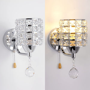 The Luxury Cylinder Wall Light, a chrome modern sconce with a crystal grid shade and pull chain featuring a crystal pendant, is shown unlit on the left and illuminated on the right—ideal luxury lighting for any space.
