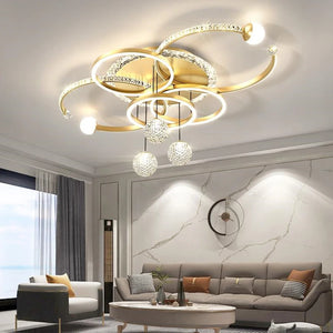 Modern living room featuring the Elegant Multi-Ring Ceiling Light in a sculptural circular LED chandelier design, complemented by a grey sofa, glass coffee table, marble accent wall, and a large window with sheer curtains.