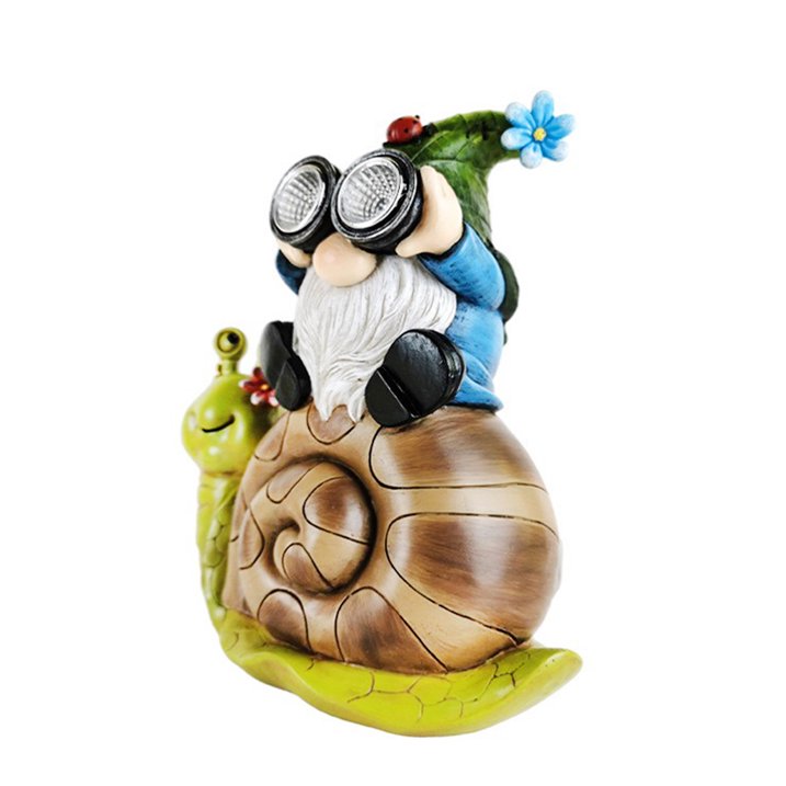 Brighten up your garden decor with the Solar Gnome Snail Light, featuring a whimsical gnome sporting a green hat and oversized goggles as he sits atop a cheerful, smiling brown snail while holding a flower. This delightful scene serves as an enchanting garden solar light, gently illuminating your outdoor space while adding playful charm and character.