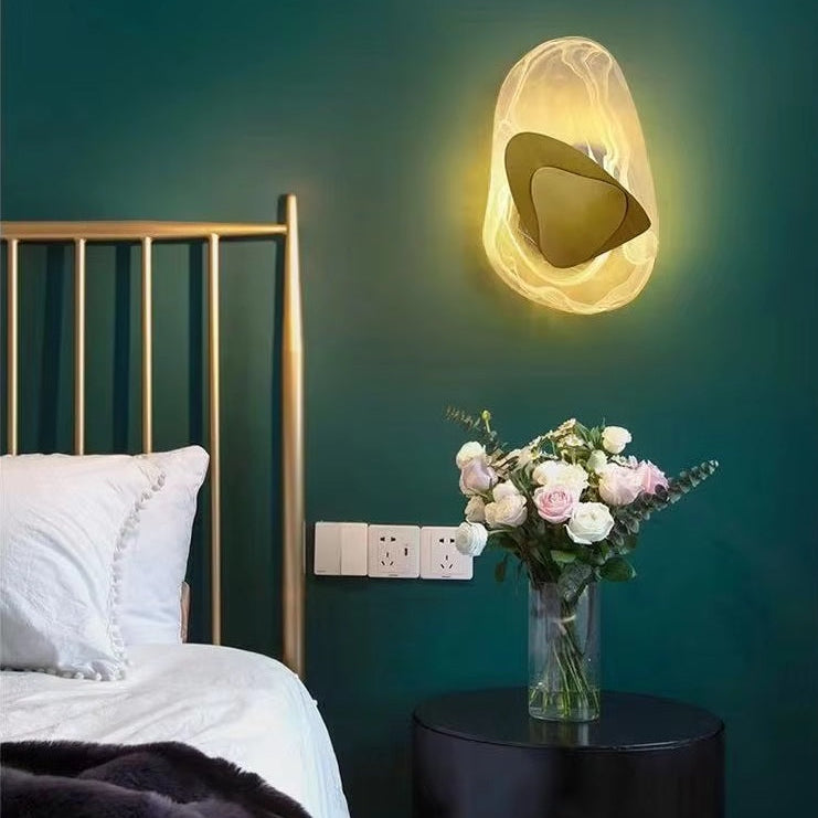 A bed featuring a gold headboard and white bedding sits beside a round table topped with a vase of flowers, while the Luxury Crystal Wall Lamp casts light across the green wall.