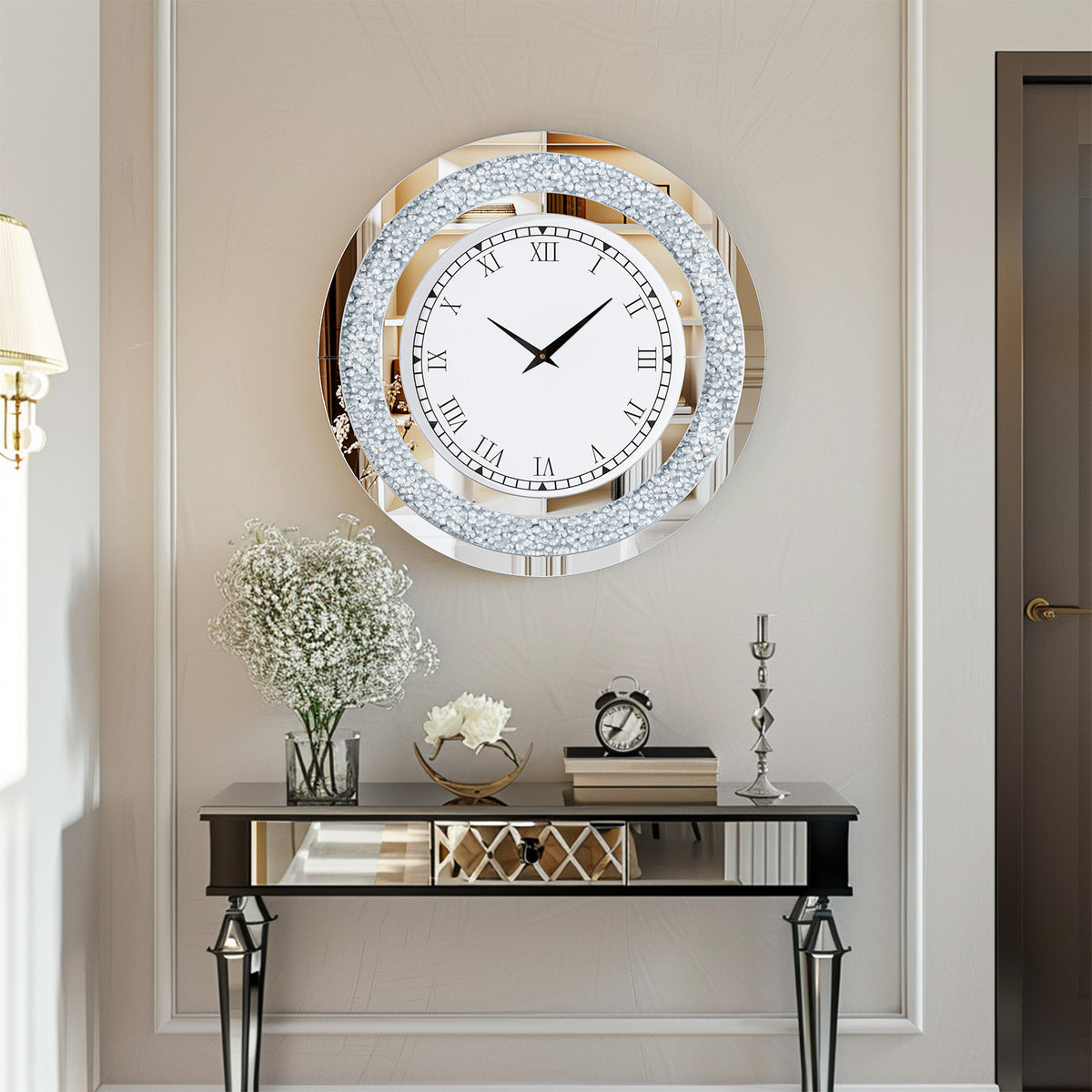 A Modern Luxury Roman Numerals Wall Clock hangs above a mirrored console table displaying a vase of white flowers, books, and decor, enhancing the modern style of this neutral-toned room.