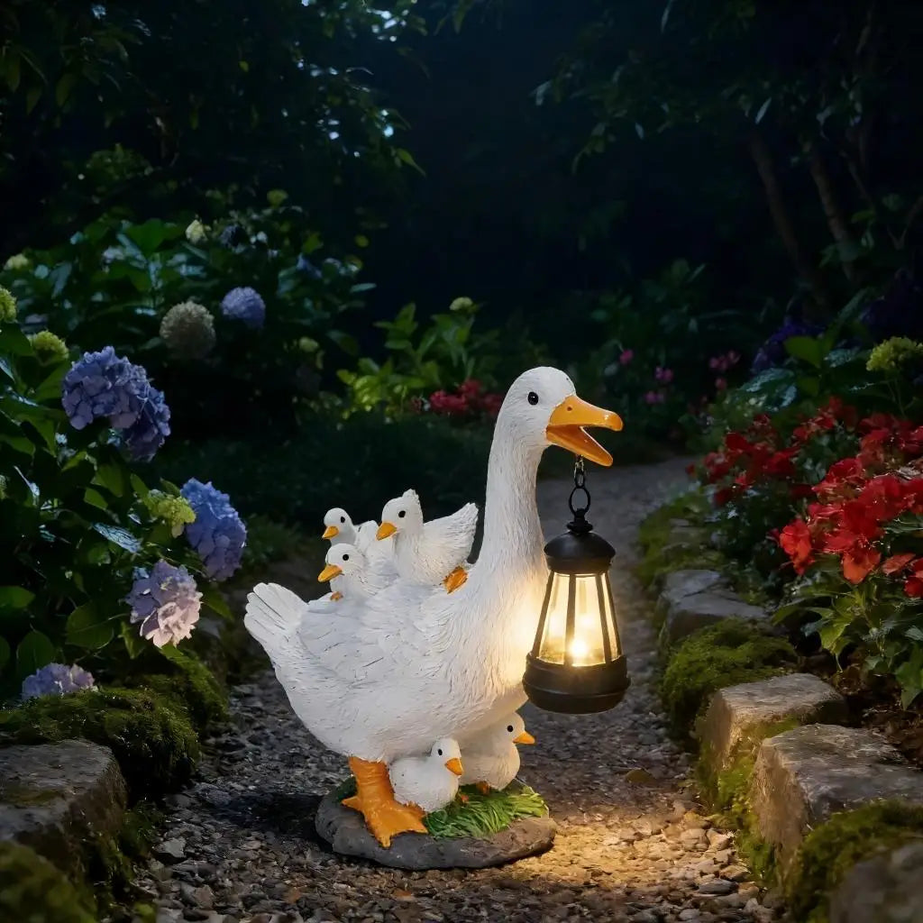 The Solar Duck Lamp stands on a stone garden path among blooming flowers at night, holding a solar-powered lantern and surrounded by gosling statues.